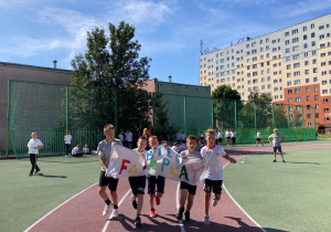 Uczniowie biegnący w strojach sportowych