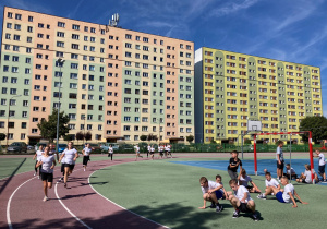 Uczniowie biegnący w strojach sportowych
