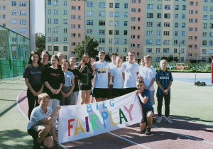 Uczniowie w strojach sportowych trzymające bilbord z napisem Fair Play