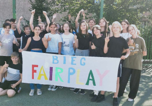 Uczniowie w strojach sportowych trzymające bilbord z napisem Fair Play