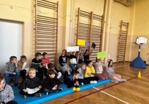 Dzieci siedzące na materacach trzymające napisy klasa 4
