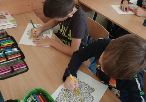 Dzieci w ławkach malujące malowankę