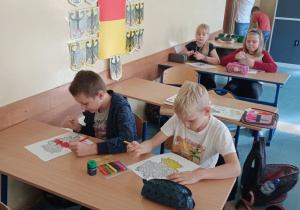 Dzieci w ławkach malujące malowankę