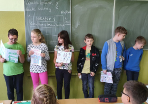 Chłopcy i dziewczynki trzymający rysunek narysowanego przez siebie komiksu