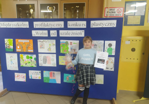 Dziewczynka stojąca na tle wystawy z rysunkami