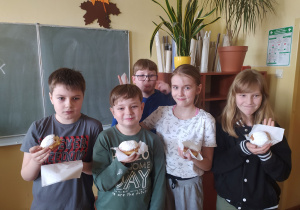 Dzieci z pączkami na tle napisu: Tłusty czwartek