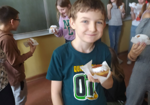 Dzieci z pączkami na tle napisu: Tłusty czwartek