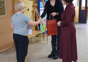 Dwie panie wręczają uczeniowi nagrodę