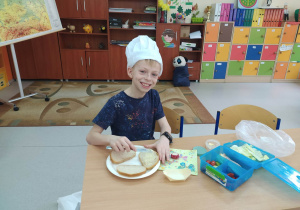 Chłopiec w czapce kucharza robi kanapki wiosenne