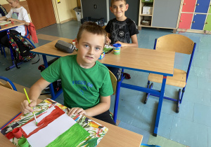 Chłopcy malują paski czerwony i zielony na fladze