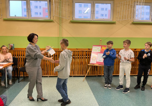 Pani wręcza dyplom chłopcu