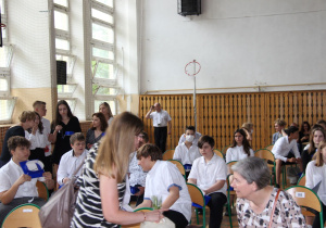 grupa uczniów siedzących na krzesłach w sali