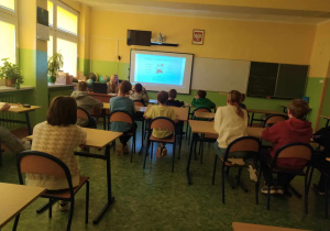 Dzieci w ławkach oglądają film na ekranie