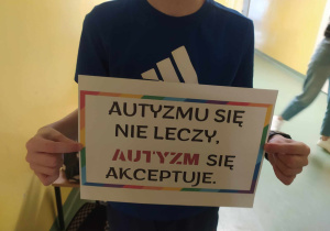 Dziecko trzyma plakat z napisem, autyzmu się nie leczy, autyzm się akceptuje.