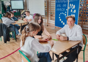 Grupa radosnych dzieci siedzi przy stoliku.