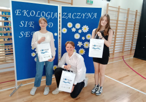 Uśmiechnięte 2 dziewczyny i chłopak z dyplomami pozują do zdjęcia.