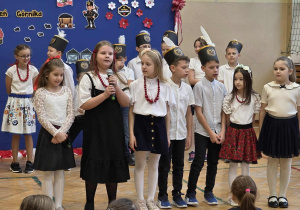 Uśmiechnięte dziewczynki w stroju galowymi i koralach oraz chłopcy w czapkach górnika