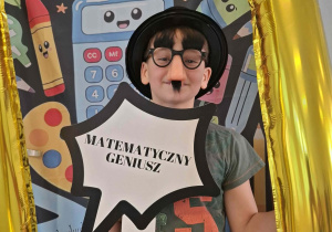 Dziecko w czarnym kapeluszu pozuje do zdjęcia w ramce
