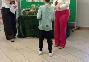 Kobieta wręcza dyplom dziecku.