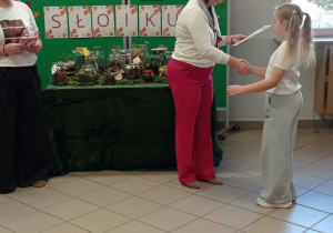 Kobieta wręcza dyplom dziecku.