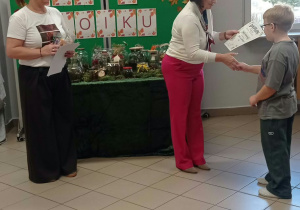 Kobieta wręcza dyplom dziecku.