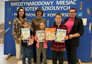 Kobiety z trójką dzieci trzymającymi dyplomy i nagrody