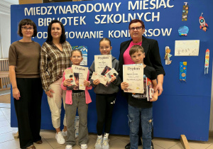 Kobiety z trójką dzieci trzymającymi dyplomy i nagrody