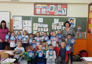 Dzieci z klasy 1b stojące w grupie dzielą się uśmiechem