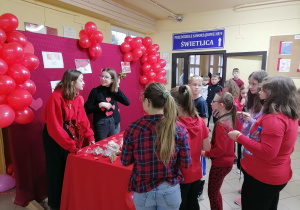 Dzieci w czerwonych strojach kupujące balony