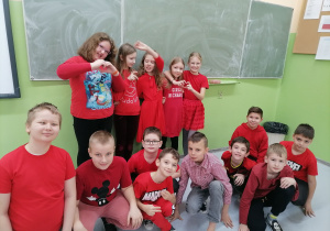 Dzieci w czerwonych strojach na tle tablicy