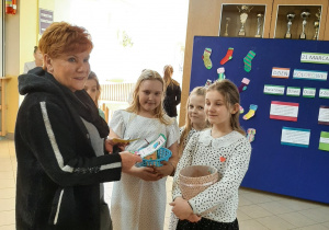 Pani z uczennicami w kolorowych skarpetkach na tle wystawy