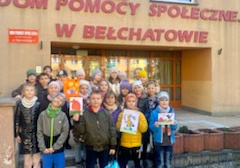 Grupa dzieci stojąca na tle budynku Domu Pomocy Społecznej w Bełchatowie