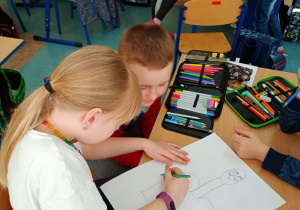 dwójka dzieci siedząca w ławce rysująca obrazek