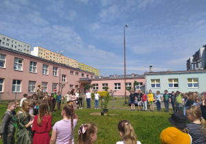 dzieci stojące w kole wokół drzewka