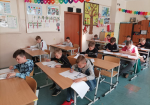 Dzieci siedzące w ławce, piszące test