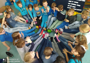 dzieci siedzące w kole, pokazujące różne skarpety