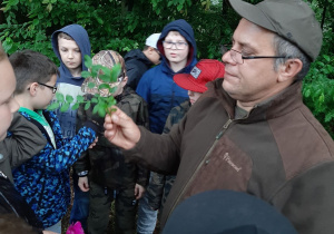 Pan leśnik trzymający w dłoni gałązkę.