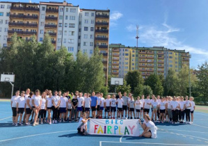 Uczniowie w strojach sportowych trzymające bilbord z napisem Fair Play