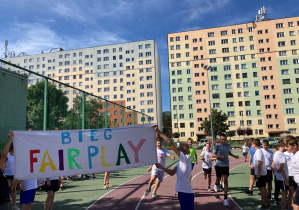 Uczniowie w strojach sportowych trzymające bilbord z napisem Fair Play