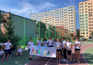 Uczniowie w strojach sportowych trzymające bilbord z napisem Fair Play