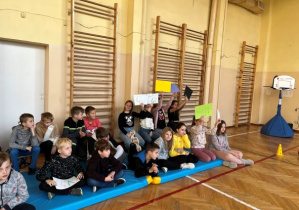 Dzieci siedzące na materacach trzymające napisy klasa 4