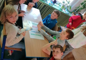 Dzieci przy stolikach grające w karty z tabliczką mnożenia