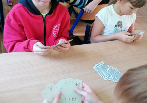 Dzieci przy stoliku grające w karty z tabliczką mnożenia