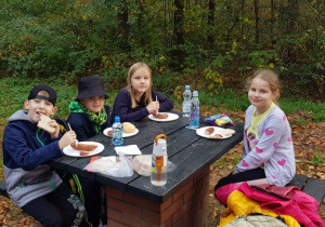 Dzieci w lesie jedzące kiełbaski