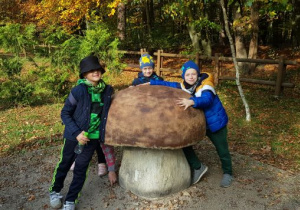Dzieci w lesie stojące przy olbrzymim grzybie
