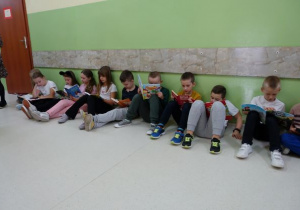 Dzieci siedzące na podłodze i czytające książki