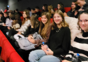 Młodzież siedząca w fotelach w sali kinowej
