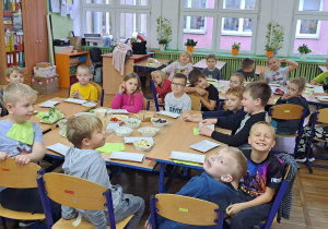 Dzieci siedzące przy stolikach z jedzeniem
