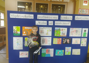 Chłopiec stojący na tle wystawy z rysunkami