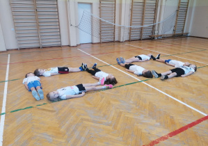 Dzieci leżące na podłodze, tworzące figury geometryczne